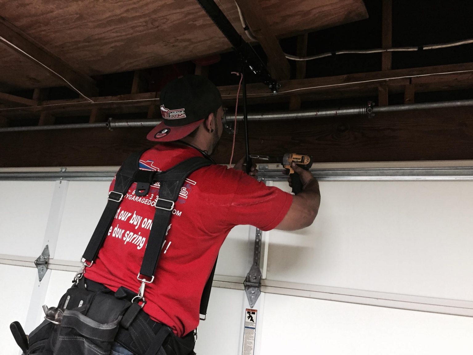 Almighty Garage Doors technician working on a garage door spring and track